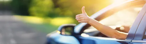 Eine Hand mit nach oben gestrecktem Daumen ragt aus einem Autofenster.