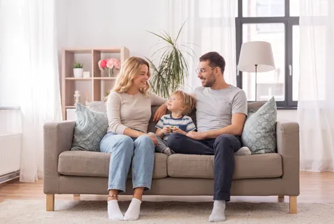 Junges Paar sitzt auf der Couch mit einem kleinen Jungen in ihrer Mitte – Bild mit mit KI erstellt.