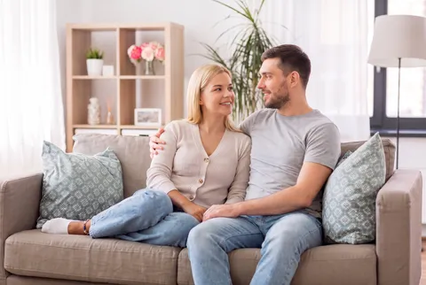 Junges Pärchen sitzt auf der Couch und schaut sich an; Bild mit KI erstellt.