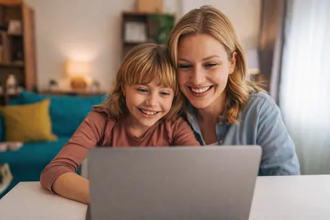 Mutter und Kind siten vor einem Laptop. Bild ist mit Hilfe von KI erstellt.