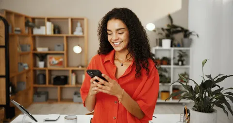 Eine lächelnde Frau sieht auf ihr Smartphone.