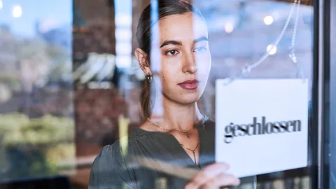 Junge Frau hinter einer Scheibe mit einem geschlossen-Türschild