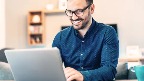 Ein lächelnder Mann sitzt tippend am Laptop.